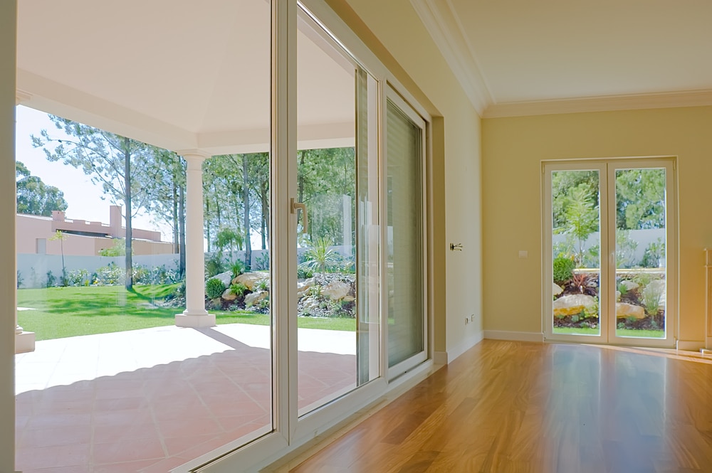 Empty room with garden view, patio doors leading out to tiled patio