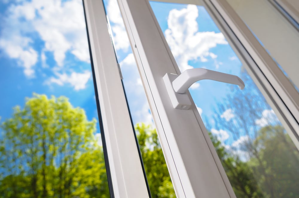 Close-up of vinyl window, open to blue sky and trees