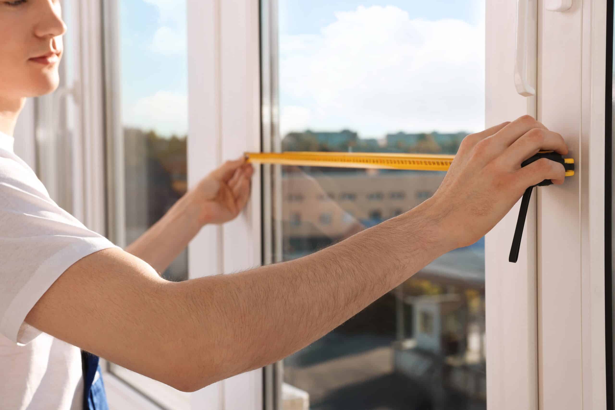 Hands measuring window with tape measure